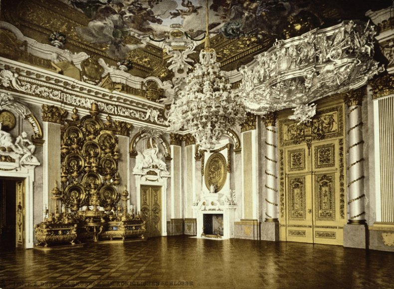 A large ornate room with gold ceiling and ornate chandelier

Description automatically generated